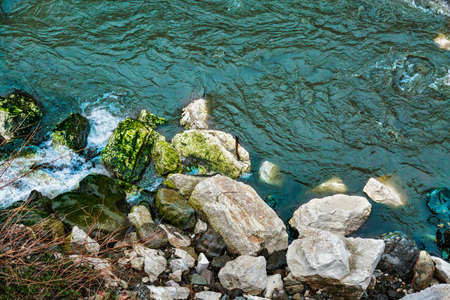 Rocky sea shore and blue water. River flowing among mossy stones. Seascape, coastline, rocks on a...