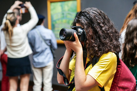 Paris, France - April 20, 2019: Young woman taking photo at exhibition inside art gallery. People visit museum Orsay (Musee d'Orsay).のeditorial素材