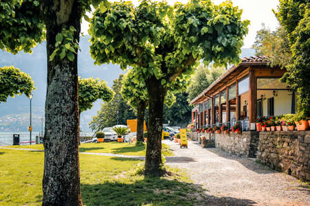 Wooden terrace of restaurant on lake Como. Cafe on quay, summer garden in Alps, Italy.