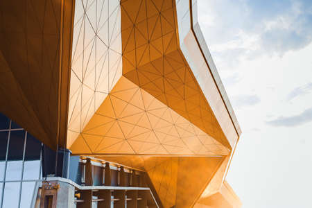 Modern architecture. Roof of complex design becoming gold by sunlight.の写真素材