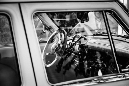 Moscow, Russia - May 30, 2021: Legendary car GAZ-21 Volga in open air. Interior of rare car with shiny steering wheel and display through window. Vintage technology. Monochrome stylized with grain.のeditorial素材