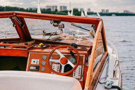 Close-up of beautiful vintage yacht for tourist in marina. Navigation implement design, buttons, dials, glass windows. City landscape, buildings on river. Romantic holiday vacation. Private journey.の写真素材
