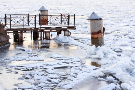 Old pier in winter. Frozen river covered by broken ice.の写真素材