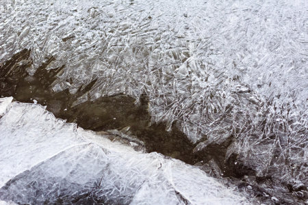 Cracked ice texture on surface of river, natural winter background, selective focusの写真素材