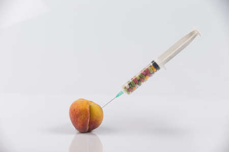 Female menopause and sexual disease metaphor: peach and syringe with meaning cosmetic and health treatment for female ageingの写真素材