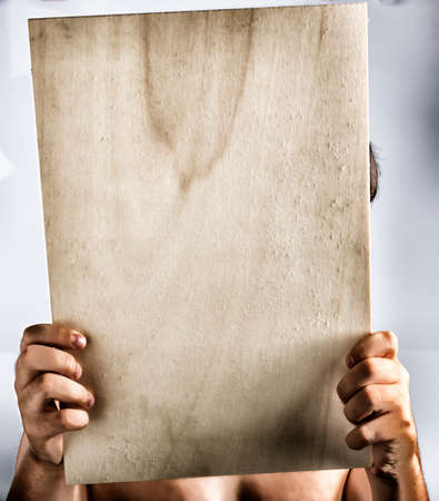 A light colour plywood square blank sign supported by young hands on light backgroundの写真素材