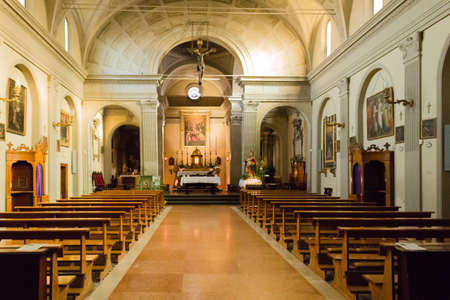 The Church of the Assumption of the Virgin Mary in  the small village of Dozza near Bologna in Emilia Romagna: interiors: Cross, altar, desks,  benches, paintings, candlesのeditorial素材