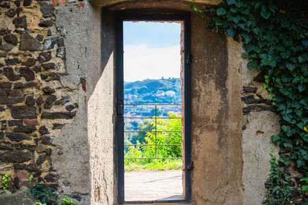 Vertical narrow medieval window in an ancient brick wall in Prague on country landscape. Green ivy. View from the Basilica of St Peter and St Paul in Vysehradの写真素材