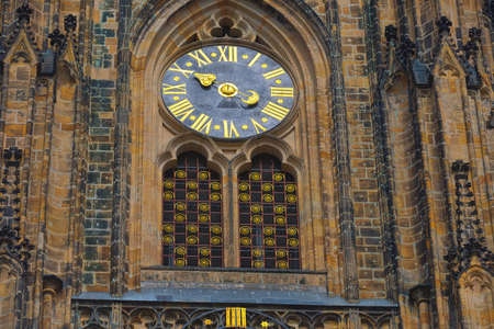 the unusual clock of the cathedral of St Vitus in Prague, a church with dark Gothic towers guarded...