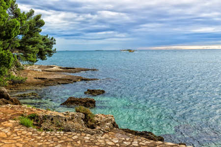 Sea view near Porec in Croatia: green trees, orange rocks and crystal watersの写真素材