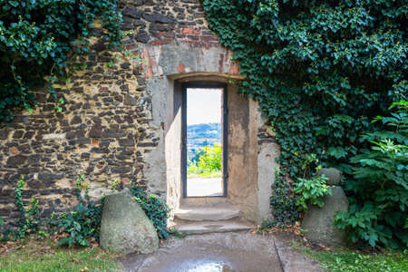 Vertical narrow medieval window in an ancient brick wall in Prague on country landscape. Green ivy. View from the Basilica of St Peter and St Paul in Vysehradの写真素材