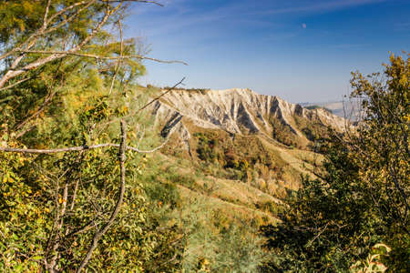 Cultivated fields of red and green leaves Vineyards during Autumn  on badlands background in Italian countryside near Brisighella in Emilia Romagnaの写真素材