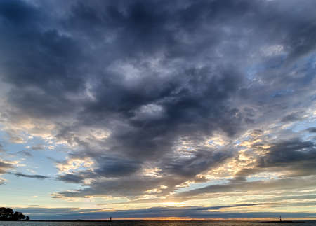 Sunset on the Mediterranean sea with red steel lookout on eyot and green top white lighthouse in the cloudy near Porec in Croatiaの写真素材