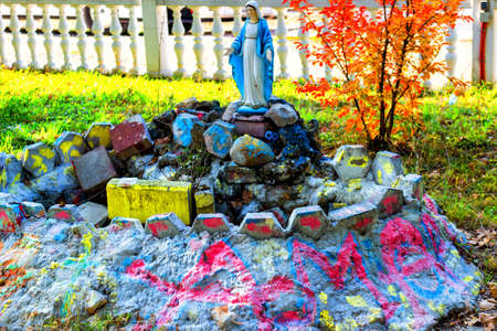 Statue of the Blessed Virgin Mary among maple tree. Green weeds and colour painted grey rocks in a garden of Medjugorjeの写真素材