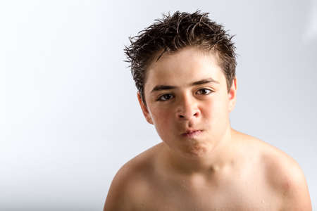 Caucasian boy with wet dark brown hair and wet skin: questioning look, puzzled and dissatisfiedの写真素材