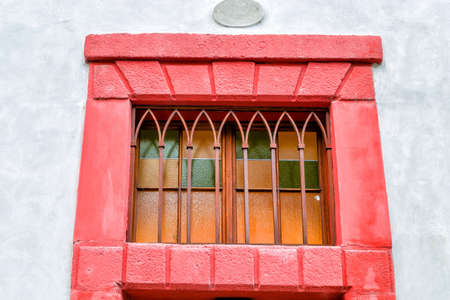Streets and buildings of Mala Strana quarter in Prague: red window with iron bars