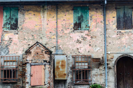Rusty windows and doors in ruined wall of an old farmhouse in countryside in Emilia Romagna in Italyの写真素材