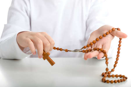 An Italian boy holds Rosary beads with both hands. He wears long sleeved shirtの写真素材
