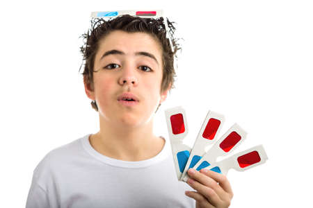 A cute Caucasian boy wears a pair of 3D Cinema paper eyeglasses on his head with red and sky-blue lenses and holds other 4 ones with left handの写真素材