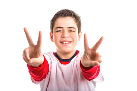 A handsome Caucasian boy makes double victory sign using both hands. He wears white shirt with red...