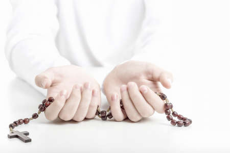 Young hands offer brown wooden rosary beads with open palms upwardの写真素材