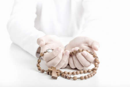 Young hands offer brown wooden rosary beads with open palms upwardの写真素材