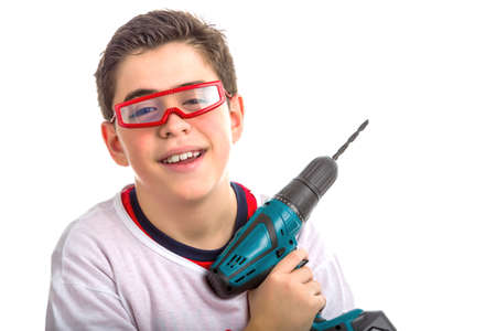 A Hispanic child wears red glasses with clear lenses and with right hand he holds a green cordless drill smilingの写真素材