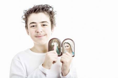A hispanic boy holds Icons in a wooden rounded case of Merciful Jesus and Our Lady of Medjugorje, the Blessed Virgin Maryの写真素材