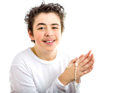 A Caucasian boy is praying and he holds Rosary beads with both hands