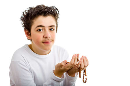 A Caucasian boy is praying and he holds Rosary beads with both handsの写真素材