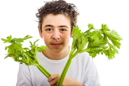 Handsome hispanic boy in white long sleeved t-shirt is smiling while holding green celery sticks with both handsの写真素材