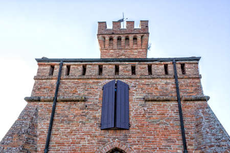 A  medieval crenellated brick wall clock tower in a sunny winter dayの写真素材