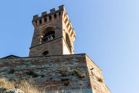 A  medieval crenellated brick wall clock tower in a sunny winter dayの写真素材