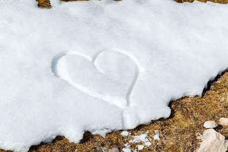A heart drawn by hand in the fresh snowの写真素材