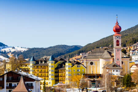 Panorama of Ortisei, Italian village in Dolomites Alps in Italy: homes, buildings and parish church...