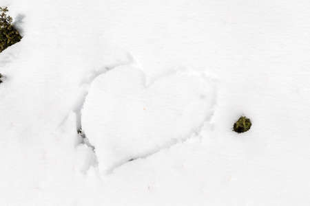 A heart drawn by hand in the fresh snowの写真素材