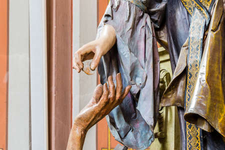 Right hand of wood carved statue of rich woman giving coin to left hand of beggar as charity gestureの写真素材