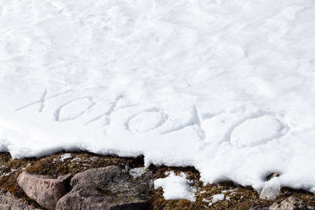 Xoxoxo meaning Hugs And Kisses, written in capital letters on frozen white snow while brown weeds and moss in the foregroundの写真素材