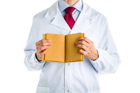 Caucasian male doctor dressed in white coat, blue shirt and red tie is showing a blank cork bookの写真素材