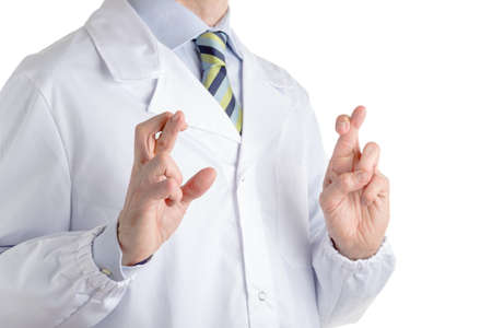 Man dressed with medical white coat, light blue shirt and glossy regimental tie with dark blue, light blue and green stripes, is crossing fingers as superstitious gestureの写真素材