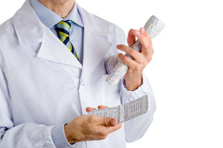 Man dressed with medical white coat, light blue shirt and glossy regimental tie with dark blue, light blue and green stripes, is holding  3d print lightbulb, flashlight and mobile phoneの写真素材