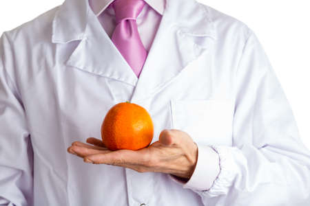 bust of a man wearing medical white coat, pale fuchsia shirt and glossy fuchsia tie and showing an orange with right handの写真素材
