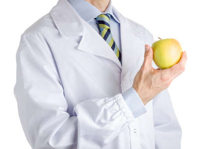 bust of a man wearing medical white coat, light blue shirt and glossy regimental tie white dark blue, light blue and green stripes, and showing yellow apple with right handの写真素材