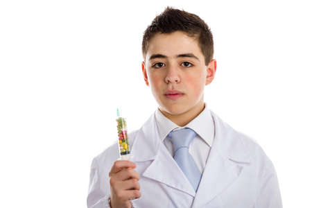 A child doctor with acne skin in white coat holding a syringe full of pills helps to feel medicine more friendly. No skin retouchingの写真素材