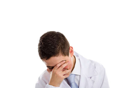 A boy doctor in white coat and blue tie helps to feel medicine more friendly: he is smiling while covering his face. His acne skin has not ben retouchedの写真素材