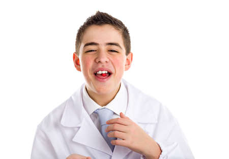 Boy dressed as a doctor in light blue tie and white coat helps to feel medicine more friendly: he is showing his tongue with a pill on it. His acne skin has not ben retouchedの写真素材