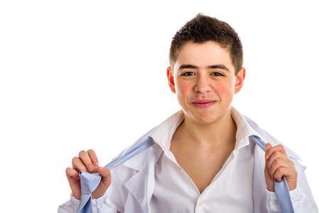 Pimply but handsome boy doctor tired but serene while undressing: he is untying the knot of the light blue tie and opening his white shirt. His acne skin has not ben retouchedの写真素材