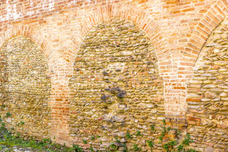 green grass and ancient brick wall of military fortification of 1400 in Northern Italy in Emilia Romagna, in the centre of the small old country village of Riolo Terme.の写真素材