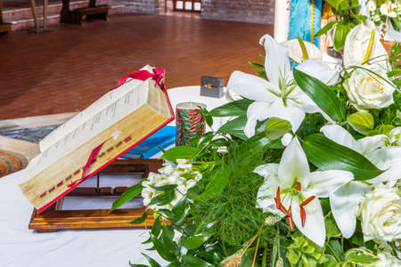 Antique Book on the altar for the celebration of Holy Mass in a Catholic Italian church with white flowers and green leaves as ornamentの写真素材