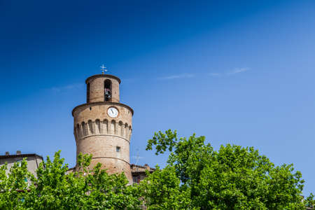 Clock tower with brick walls guarding a countryside village in Italyの写真素材